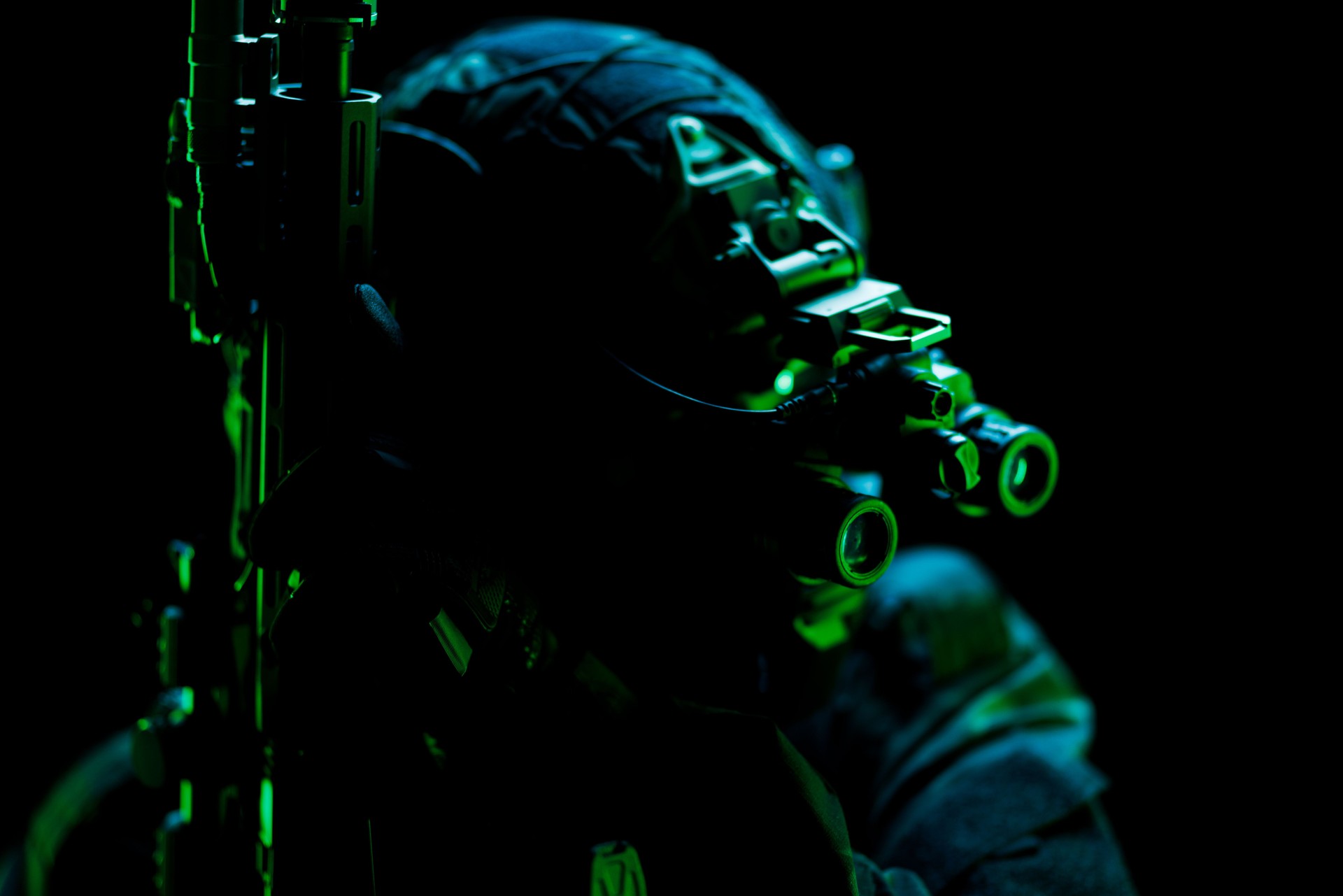 Silhouetted tactical figure in night vision equipment under green lighting Silhouetted tactical figure in night vision equipment under green lighting